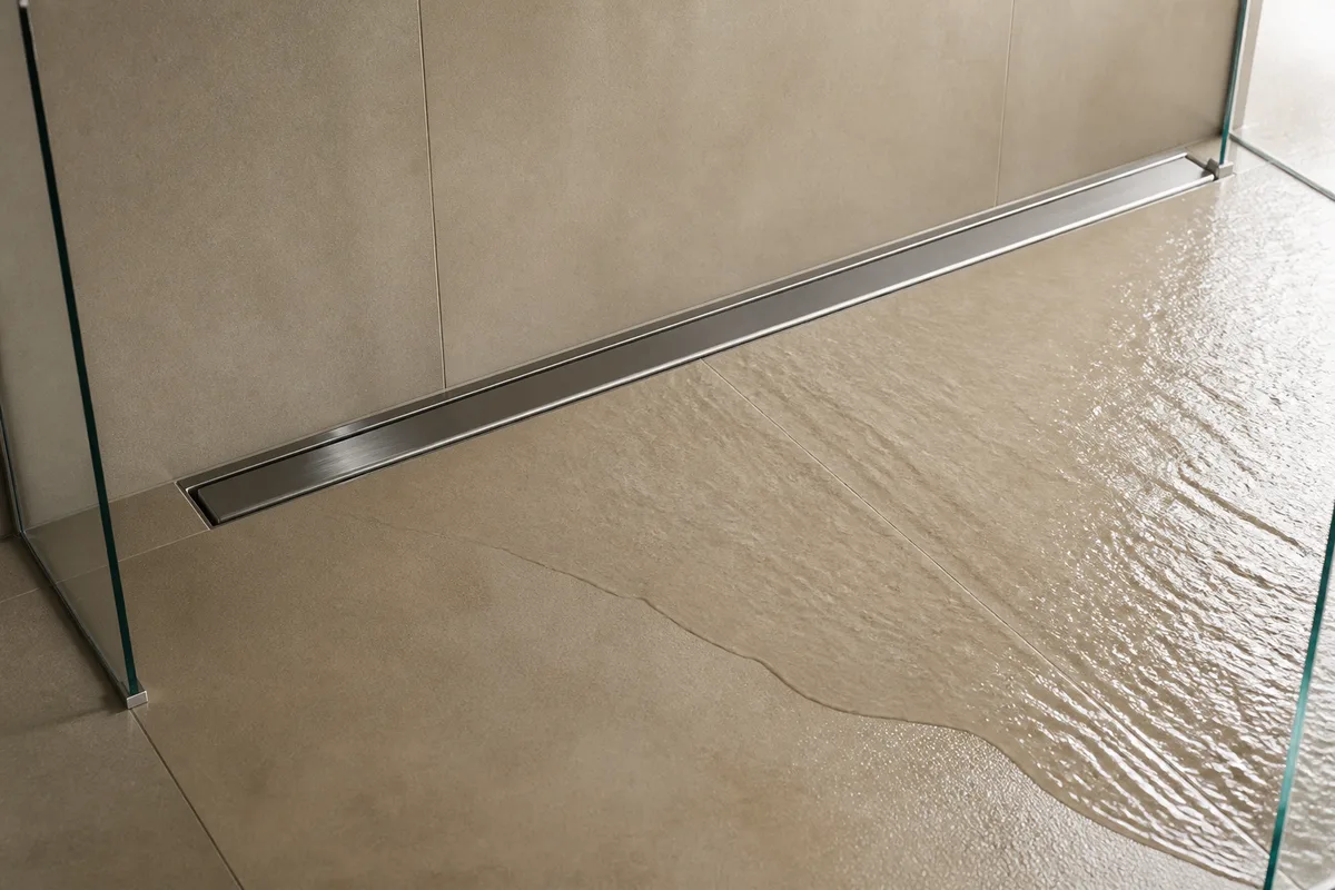Douche de plain-pied carrelée en grès clair avec caniveau linéaire le long du mur et paroi de verre à fixations fines